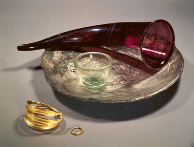 Drinking horn of red glass, a small glass beaker, a silver plate and golden finger rings from a rich woman's grave excavted in Himlingøje in 1977. The grave dates to the 3rd century AD. The first kings of the Danes?